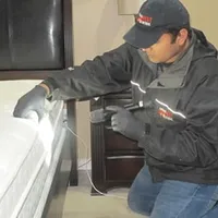 Bed bug inspection technician checking a mattress and bed frame for signs of infestation in Eugene, OR