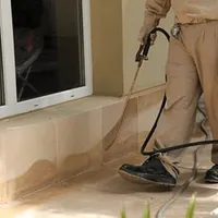 General pest control technician spraying exterior perimeter around a home in Eugene, OR